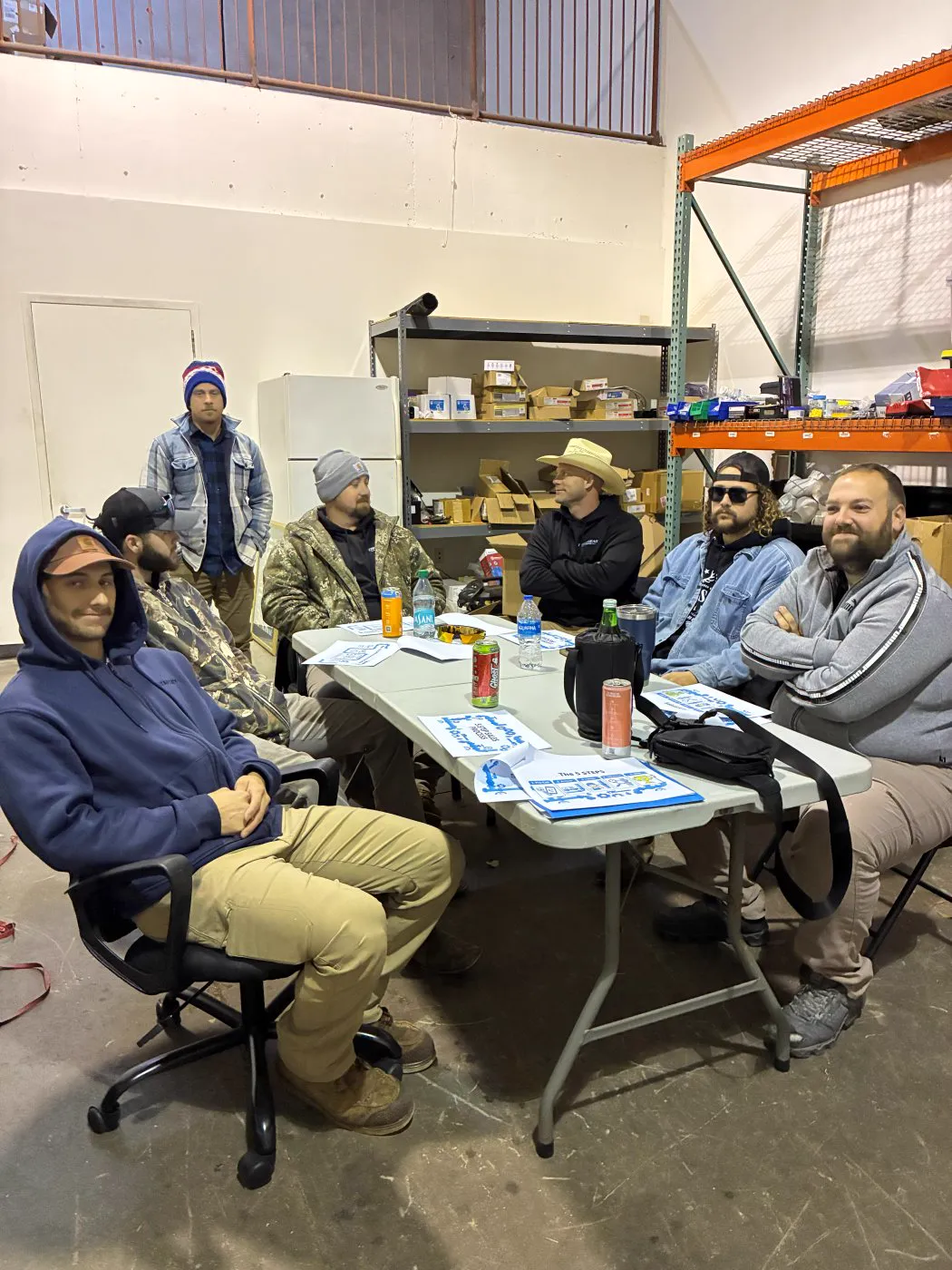 Technicians gathered around a table in a warehouse during training